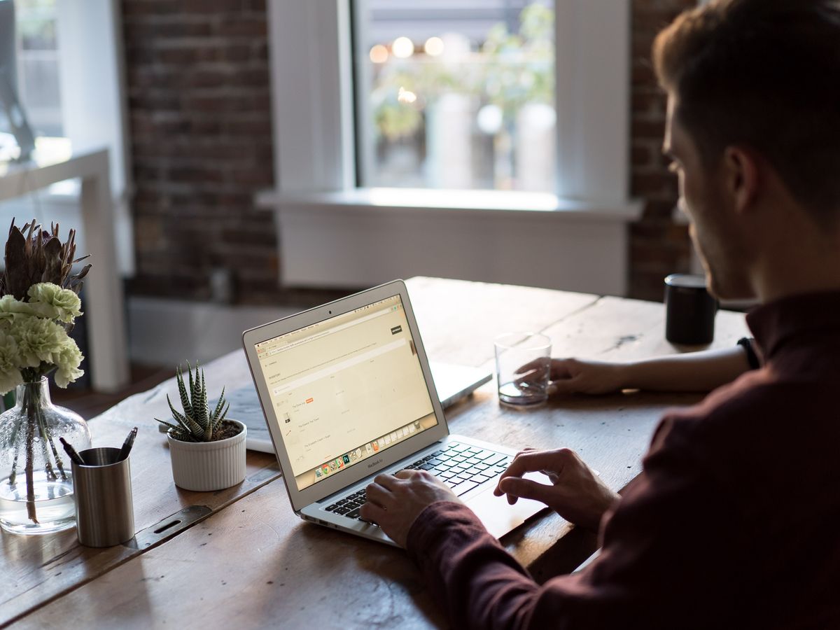 A designer at a laptop by a sunny window