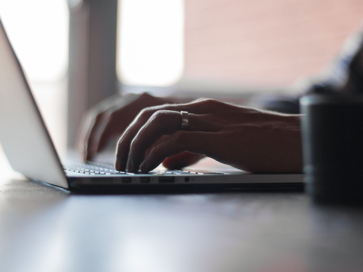 Hands typing on a laptop