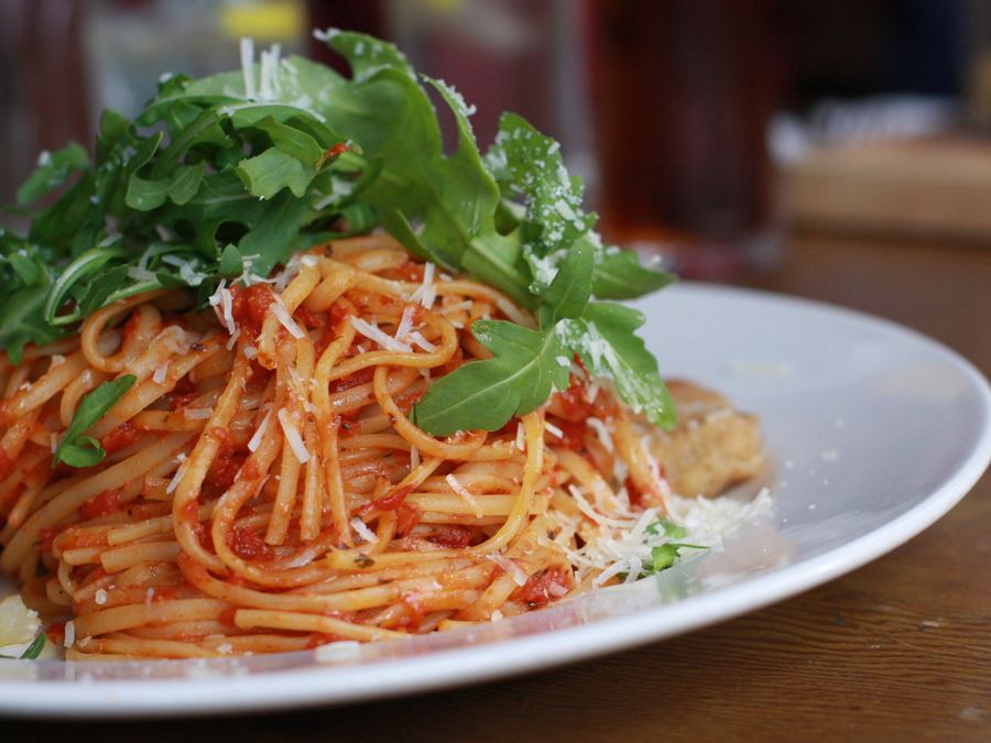 Spaghetti in tomato sauce under rocket and shaved cheese