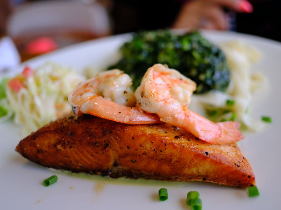 Seared salmon topped with shrimp, beside creamed spinach
