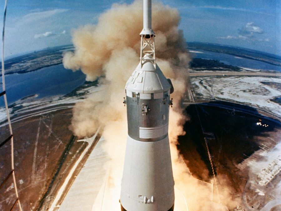 A Saturn V rocket clearing the launch tower in fire and smoke, seen from above